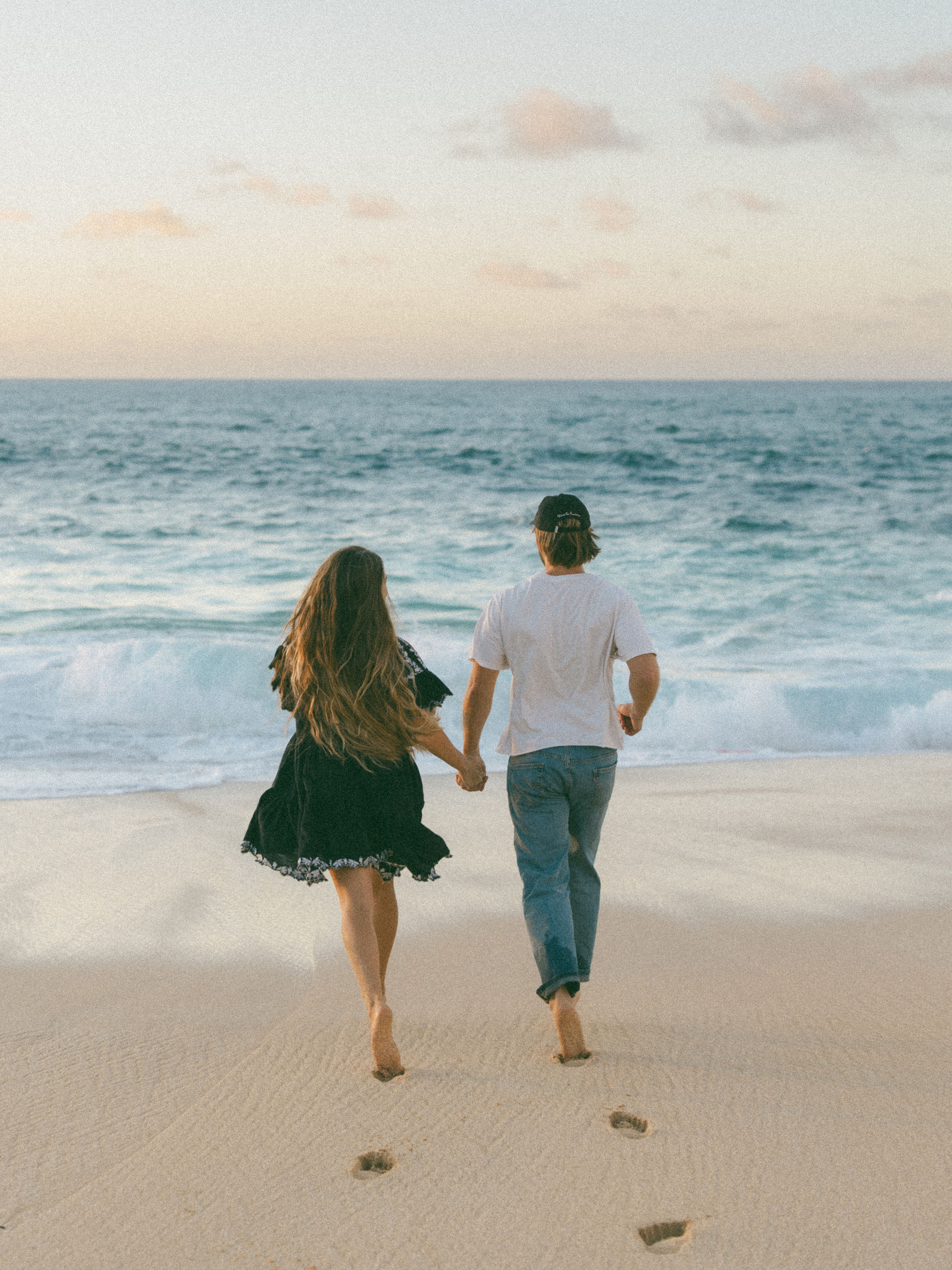 Couple walking on beach at sunset