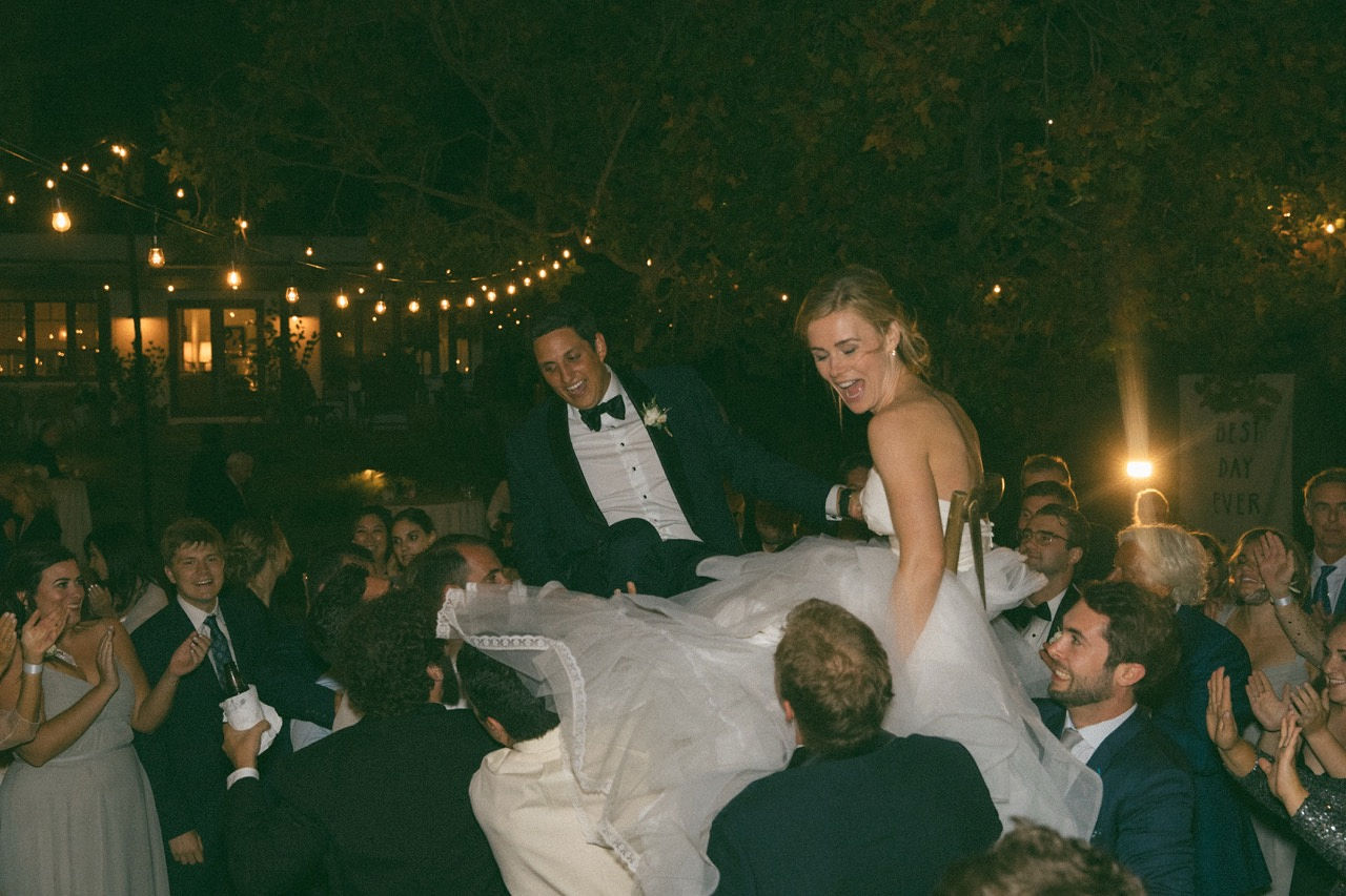 Couple lifted by guests at reception