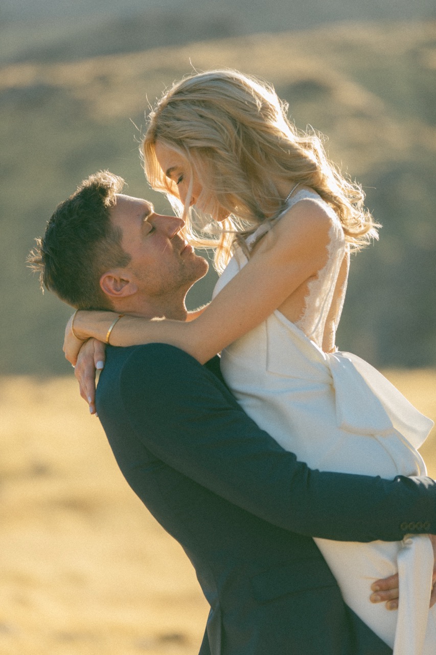 Groom lifting bride at golden hour