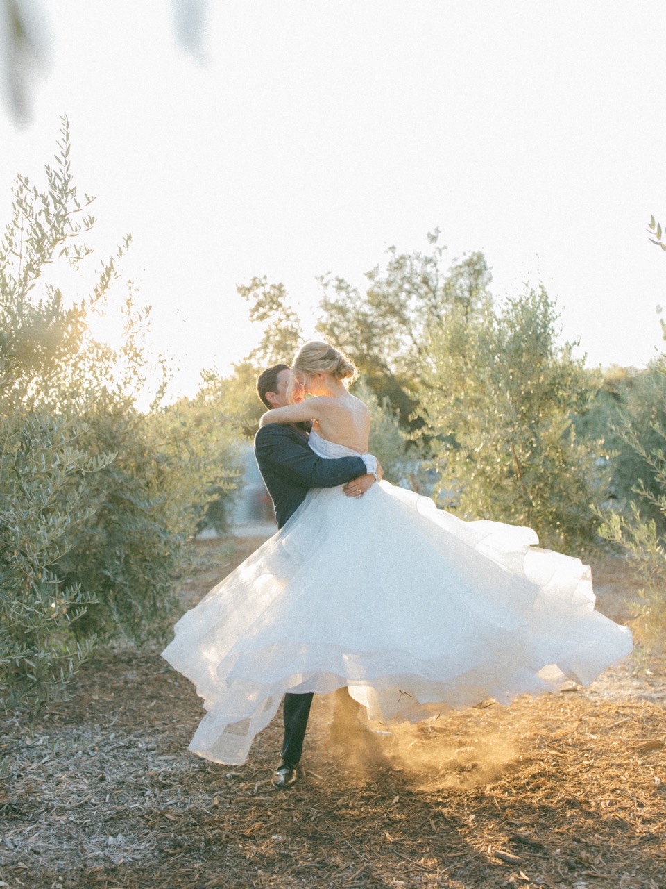 Couple spinning in olive grove at golden hour