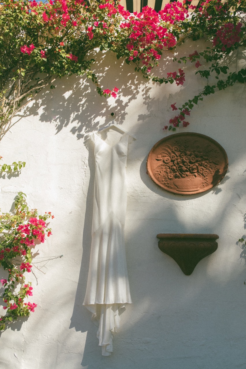 Dress hanging on white wall with bougainvillea