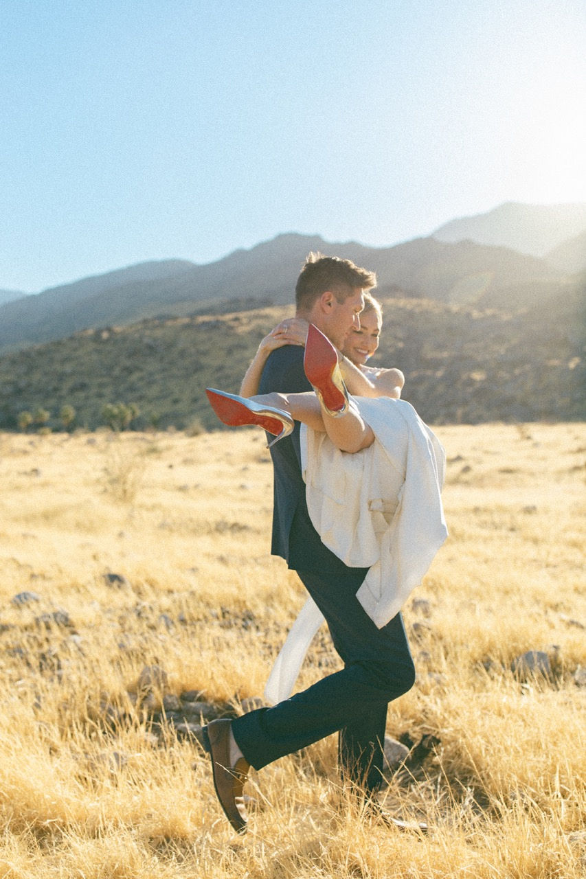 Groom carrying bride in golden field