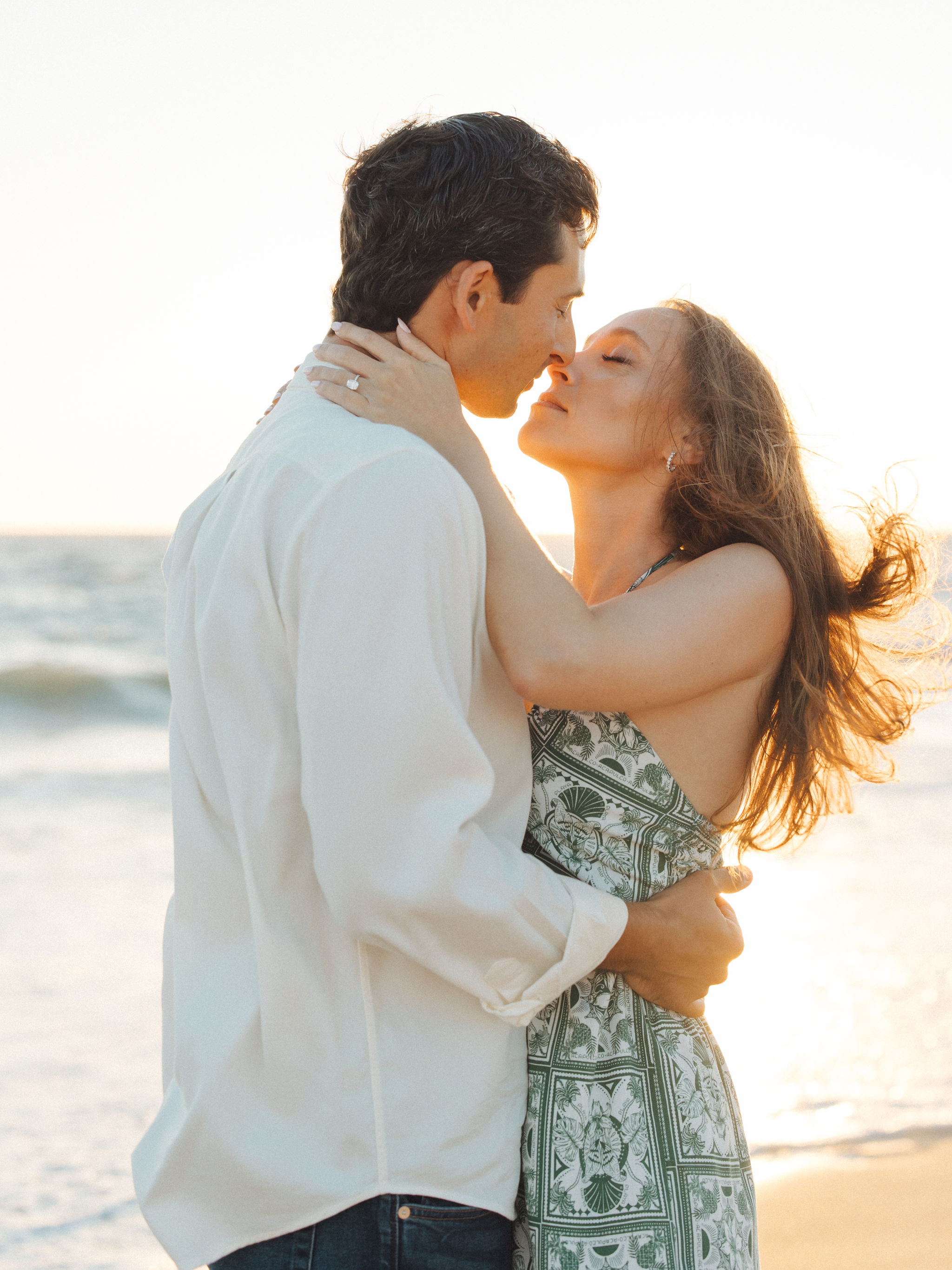 Couple kissing at golden hour with engagement ring visible