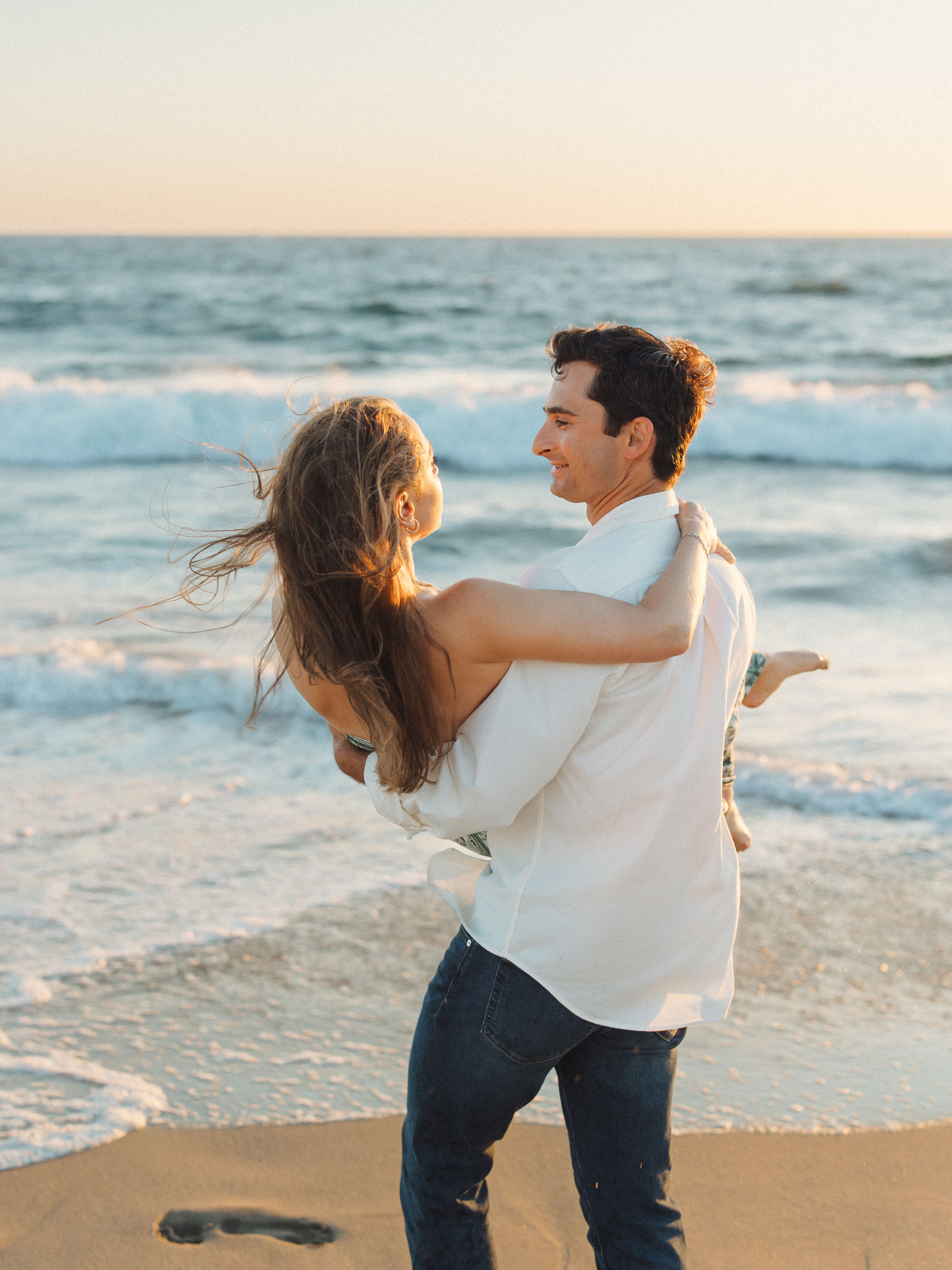 Man lifting woman on the beach at sunset
